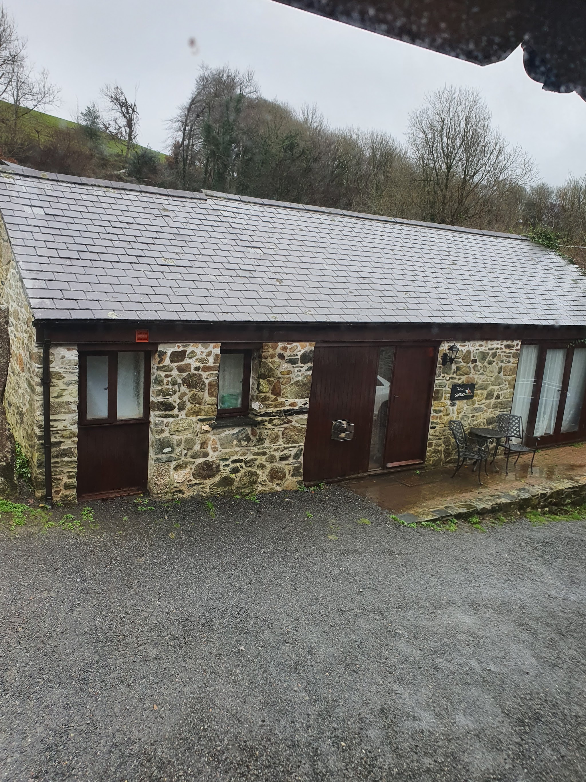 A single-storey stone cottage with a slate roof on the gravel yard