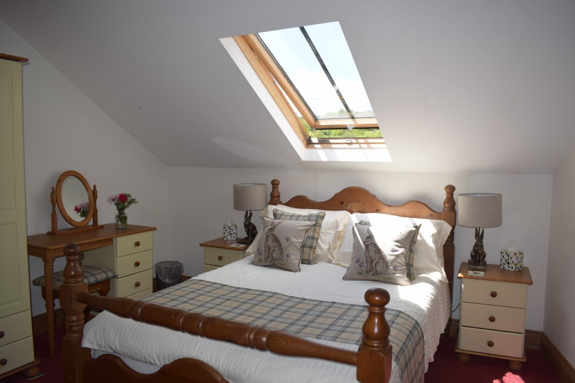 A Charlotte's Barn Top bedroom with a pine double bed under a skylight