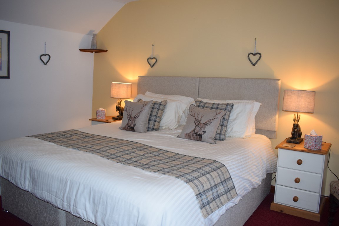 A Clearbrook Barn bedroom with a double bed, tartan throw and bedside lamps