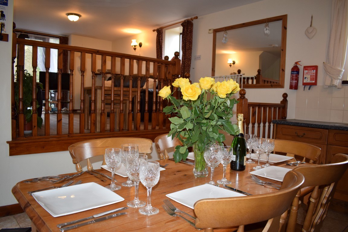 A cottage dining table laid with glasses and yellow flowers