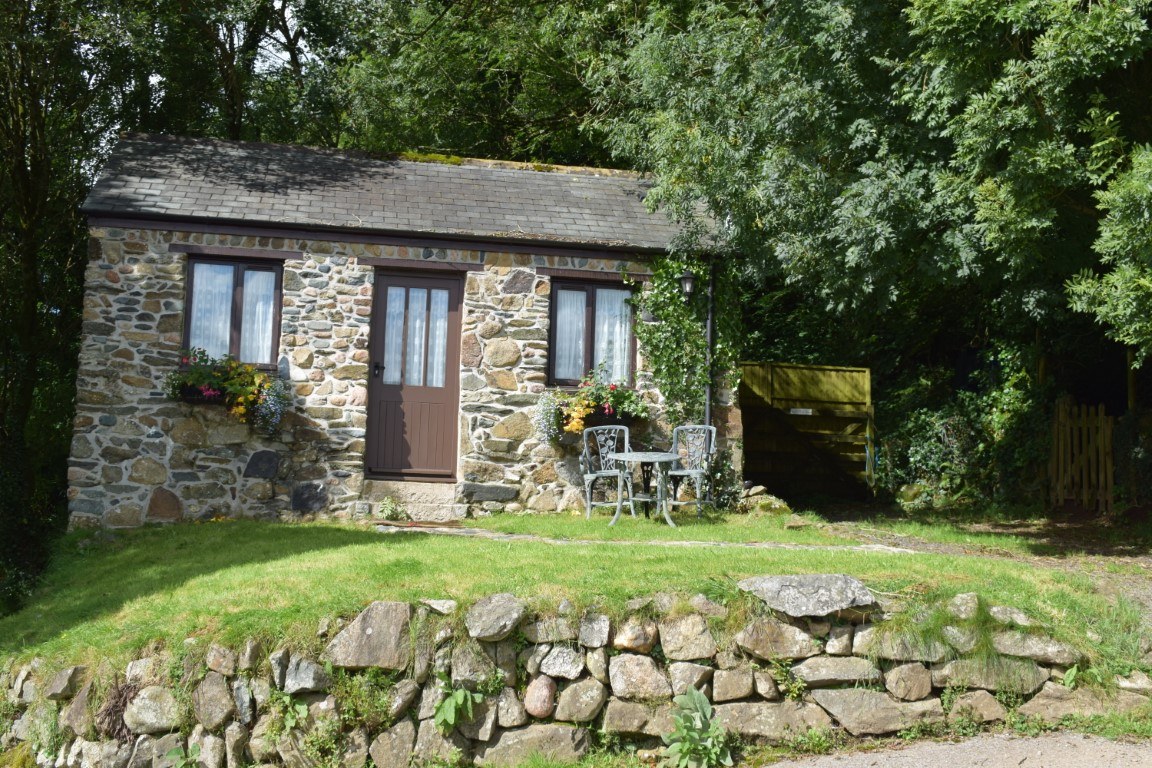 Pond Cottage, a small stone cottage above a dry-stone wall with a garden table