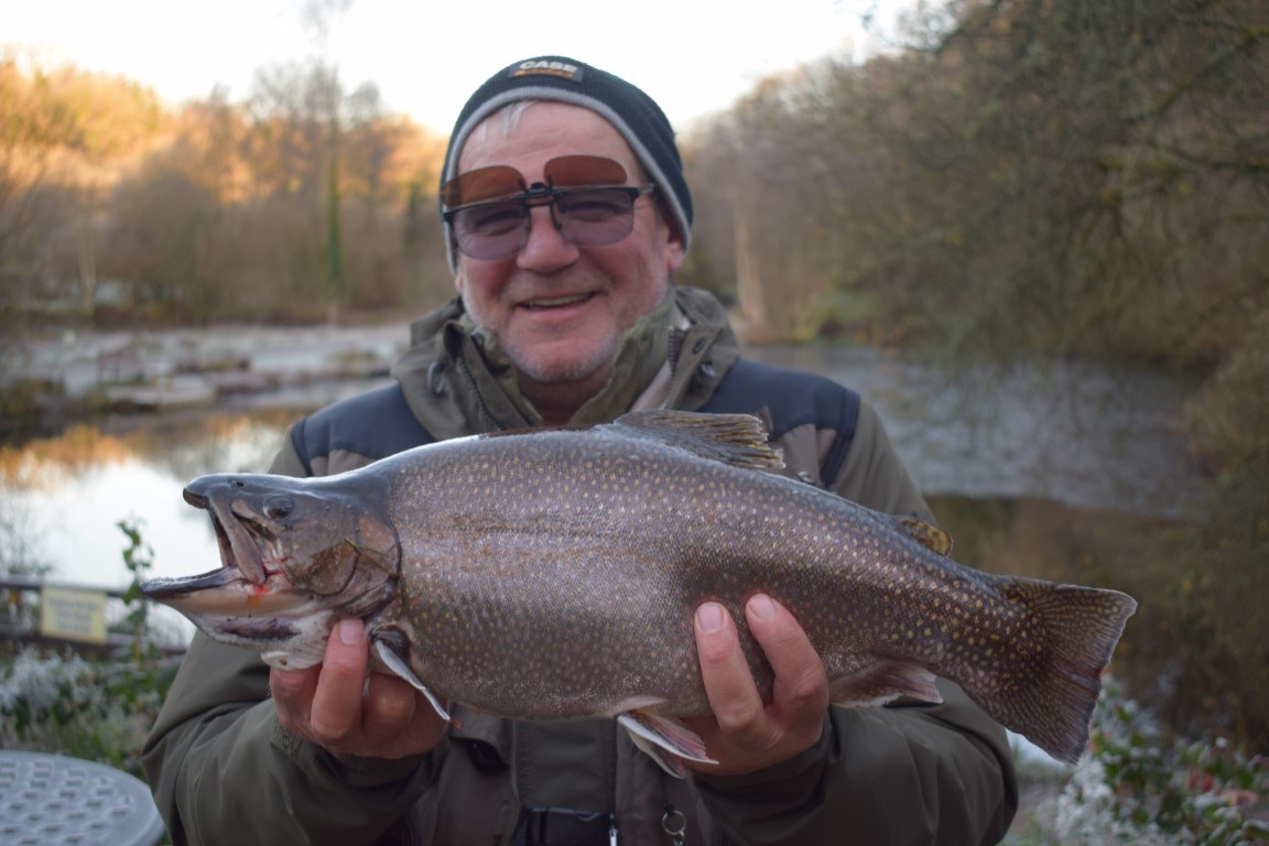 An angler in sunglasses holding a big rainbow trout