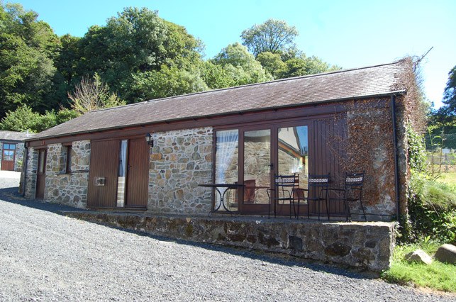 The Snug, a single-storey stone barn conversion with a timber-framed glass front